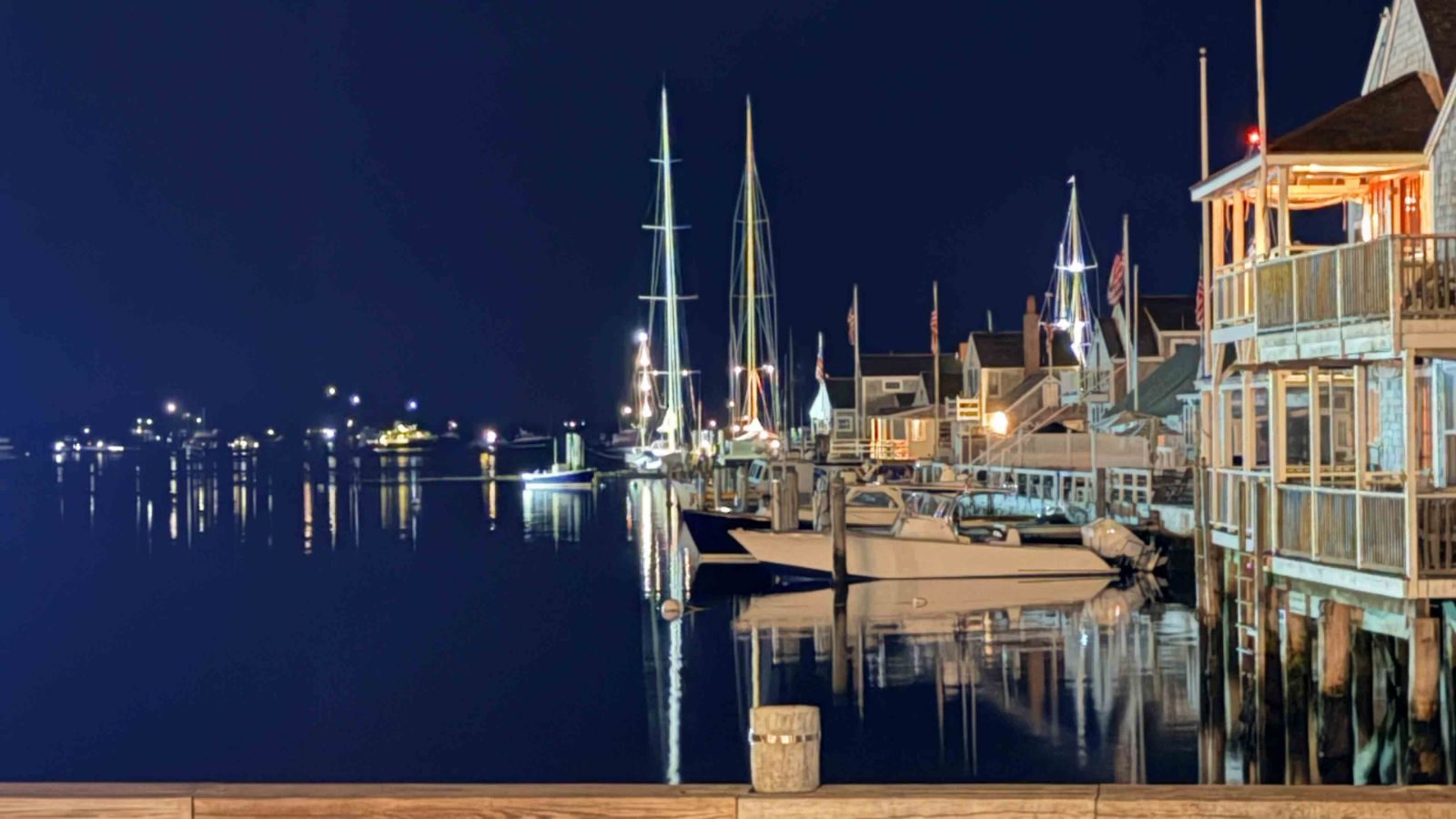 Easy Street at night, boats and lit storefronts reflected in the harbor